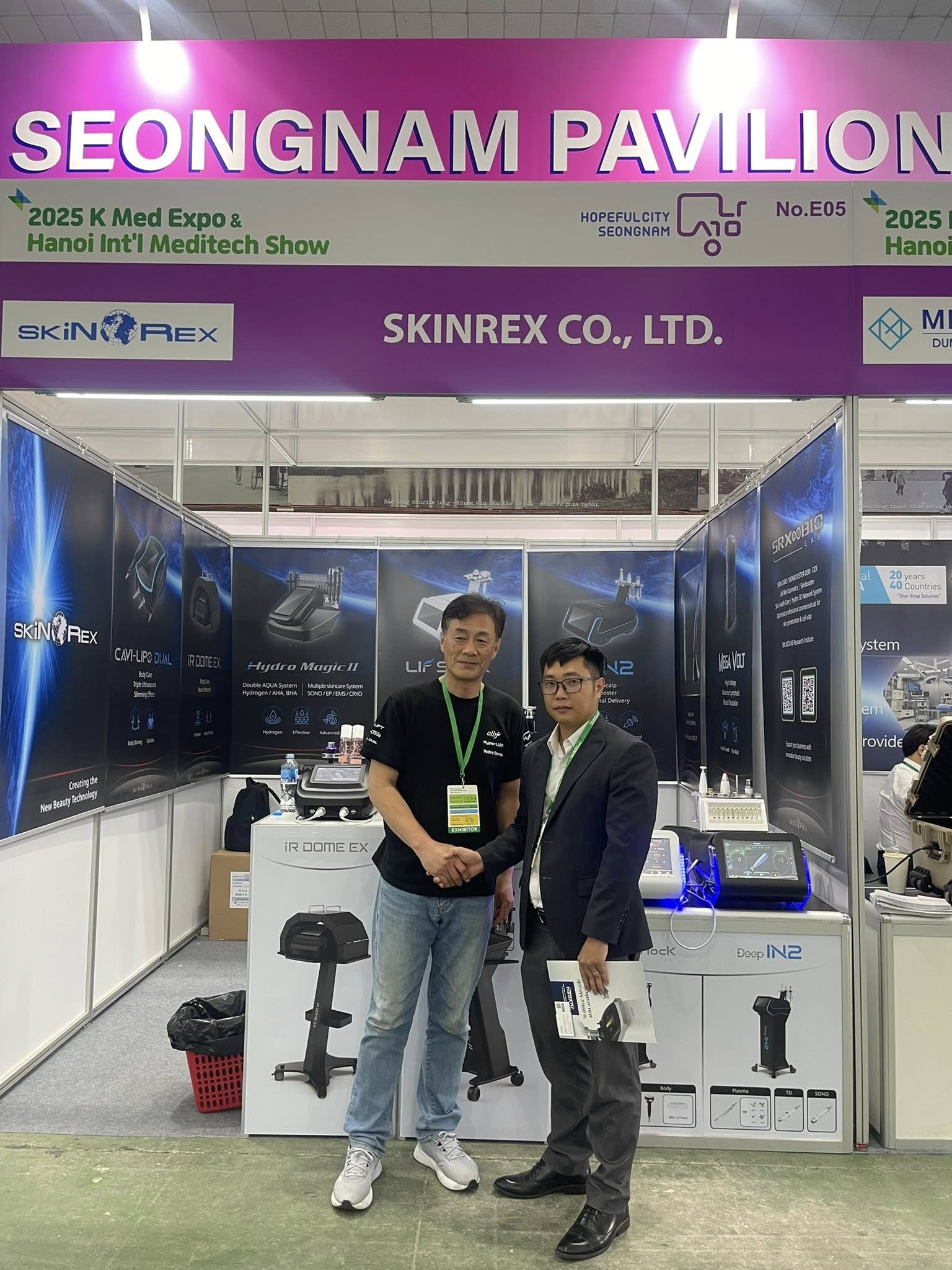 Hai người đàn ông bắt tay tại gian hàng Skinrex Co Ltd trong triển lãm y tế Seongnam Pavilion