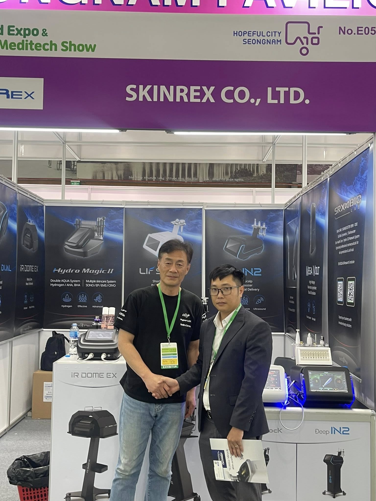 Hai người đàn ông bắt tay tại gian hàng Skinrex Co Ltd trong triển lãm thiết bị y tế